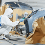 Collision repair spray technician finishing a bumper repaint in Kennewick.