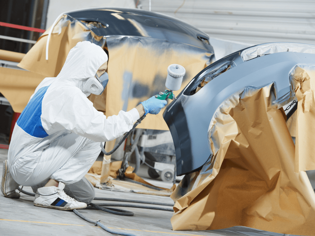 Collision repair spray technician finishing a bumper repaint in Kennewick.
